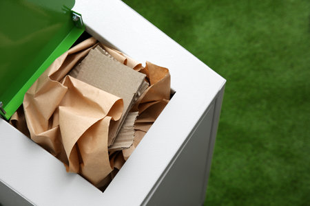 Trash bin with paper and cardboard on color background, space for text. Recycling conceptの写真素材