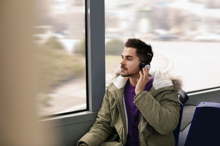 Young man listening to music with headphones in public transportの写真素材
