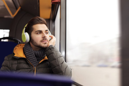 Young man listening to music with headphones in public transportの写真素材
