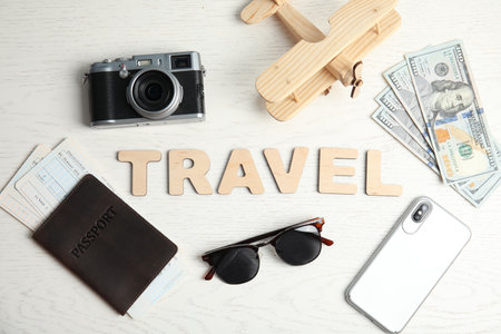 Flat lay composition with word TRAVEL, camera and passport on wooden background. tourist agencyの写真素材