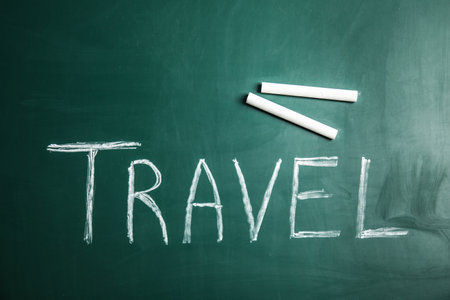 Word TRAVEL and chalk on blackboard, top view. tourist agency