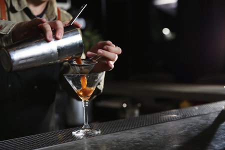 Barman pouring martini espresso cocktail into glass at counter, closeup. Space for textの写真素材