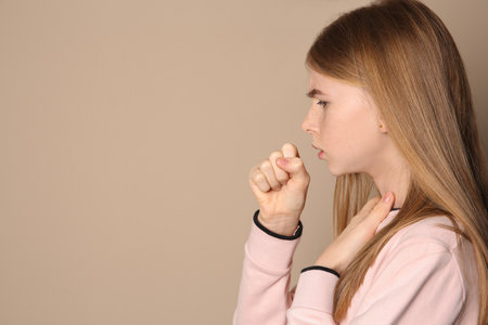Teenage girl suffering from cough on color background. Space for textの写真素材