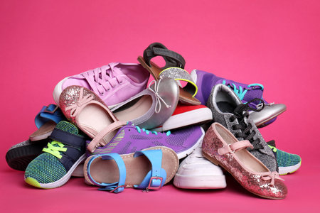 Heap of different shoes on color background