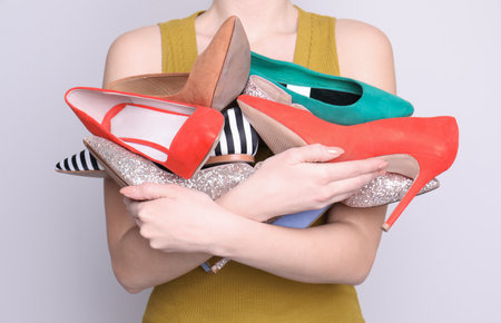 Woman holding heap of elegant shoes on light background, closeupの写真素材
