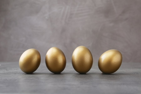Many shiny golden eggs on gray tableの写真素材