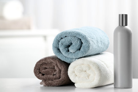 Clean towels and shampoo bottle on table. Space for textの写真素材