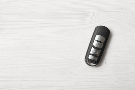 Remote car key on white wooden background, top view. Space for textの写真素材