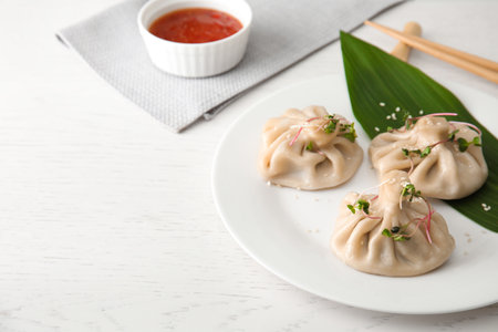 Plate with tasty baozi dumplings on white wooden table. Space for textの写真素材