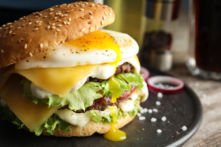 Tasty burger with fried egg on tray against blurred background, space for textの写真素材