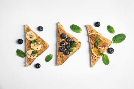 Different toasts with fruits, blueberries, peanut butter and chia seeds on white background, top viewの写真素材