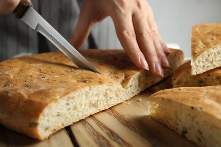 Woman cutting bread on wooden board, closeupの写真素材