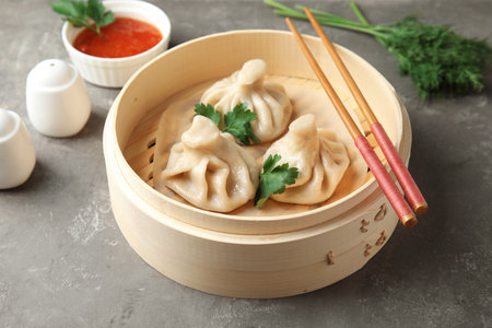 Bamboo steamer with tasty baozi dumplings and chopsticks on tableの写真素材