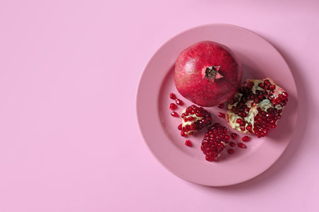 Plate with ripe pomegranates on color background, top view. Space for textの写真素材
