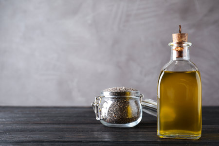 Bottle of chia oil and jar with seeds on table. Space for textの写真素材