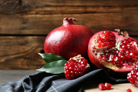 Ripe pomegranates on board against wooden background, space for textの写真素材