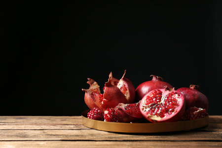 Tray with ripe pomegranates on table against black background, space for textの写真素材