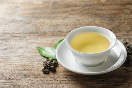 Cup of Tie Guan Yin oolong and tea leaves on wooden table. Space for textの写真素材