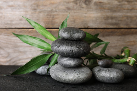 Stacked zen stones and bamboo leaves on table against wooden backgroundの写真素材