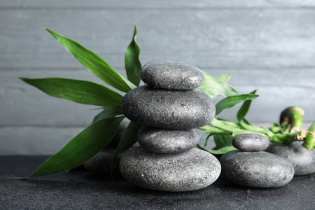 Stacked zen stones and bamboo leaves on table against wooden backgroundの写真素材