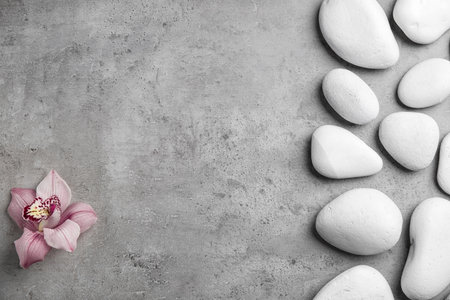 Zen stones and exotic flower on gray background, top view with space for textの写真素材