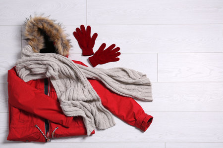 Flat lay composition with warm clothes for winter vacation on wooden background. Space for textの写真素材