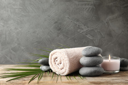 Composition with zen stones, towel and candle on table against gray background. Space for textの写真素材