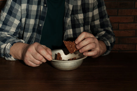 Poor senior man eating bread at table, closeupの写真素材