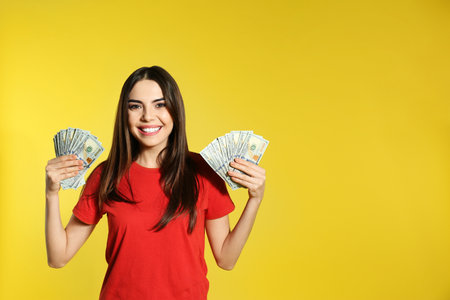Young woman with money on color background. Space for textの写真素材