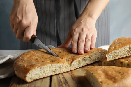 Woman cutting bread on wooden board, closeupの写真素材