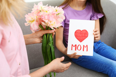 Little daughter congratulating her mature mom at home, closeup. Happy Mother's Dayの写真素材