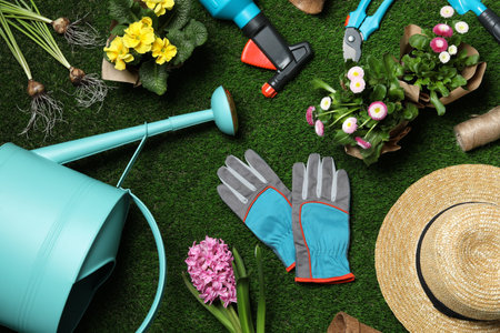 Flat lay composition with gardening equipment and flowers on green grassの写真素材