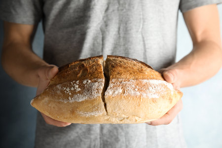 Man holding whole wheat bread on gray background, closeupの写真素材