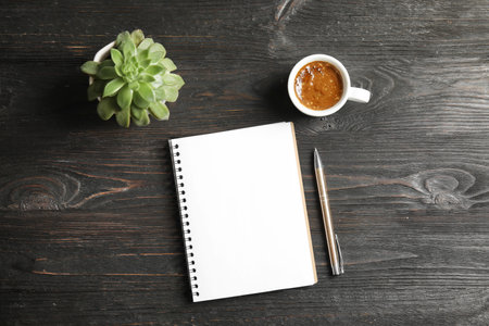 Notebook, coffee and plant on dark wooden backgroundの写真素材