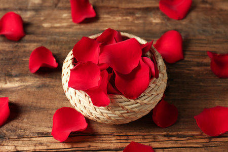Wicker basket with rose petals on wooden backgroundの写真素材
