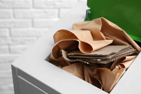 Trash bin with paper and cardboard near brick wall, closeup. Recycling conceptの写真素材