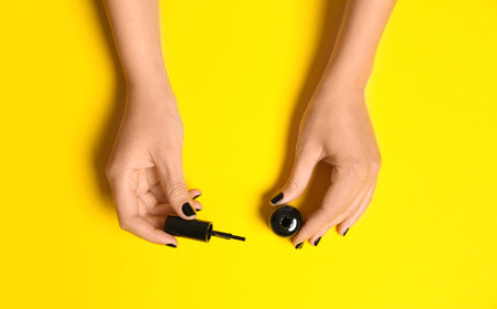 Woman applying nail polish on color background, top viewの写真素材