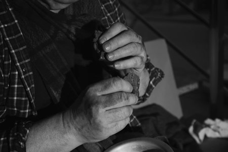 Poor senior man eating bread indoors, closeup. black and white effect