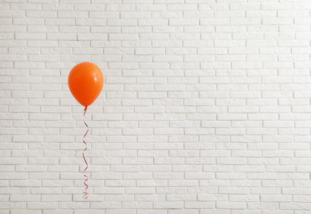 Bright balloon near brick wall, space for text. Celebration timeの写真素材