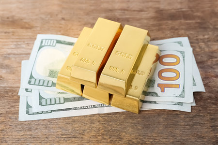 Gold bars and dollar bills on wooden tableの写真素材