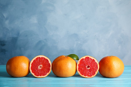 Fresh tasty grapefruits on table against color background. Space for textの写真素材