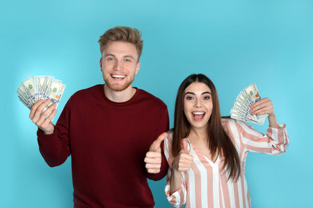 Young couple with money on color backgroundの写真素材