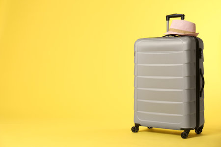 Stylish suitcase with hat on color background. Space for textの写真素材