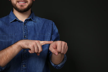 Man showing word TIME in sign language on black background, space for textの写真素材