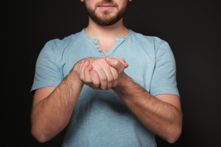 Man showing BELIEVE gesture in sign language on black background, closeupの写真素材