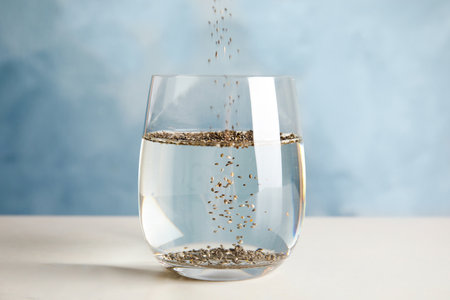 Pouring chia seeds into glass with water on tableの写真素材