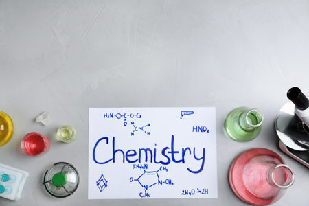 Laboratory glassware and paper with word CHEMISTRY on gray background, top view. Space for textの写真素材