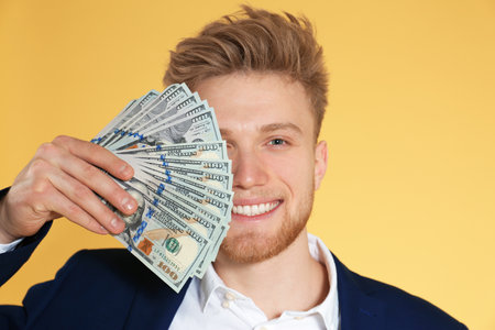 Young businessman with money on color backgroundの写真素材