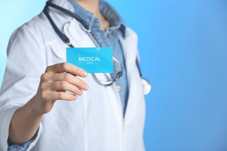 Doctor holding business card on color background, closeup with space for text. medical serviceの写真素材