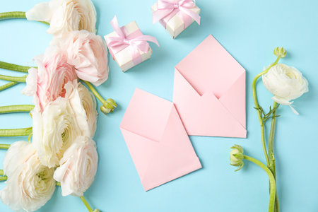 Flat lay composition with beautiful ranunculus flowers and envelopes on color backgroundの写真素材